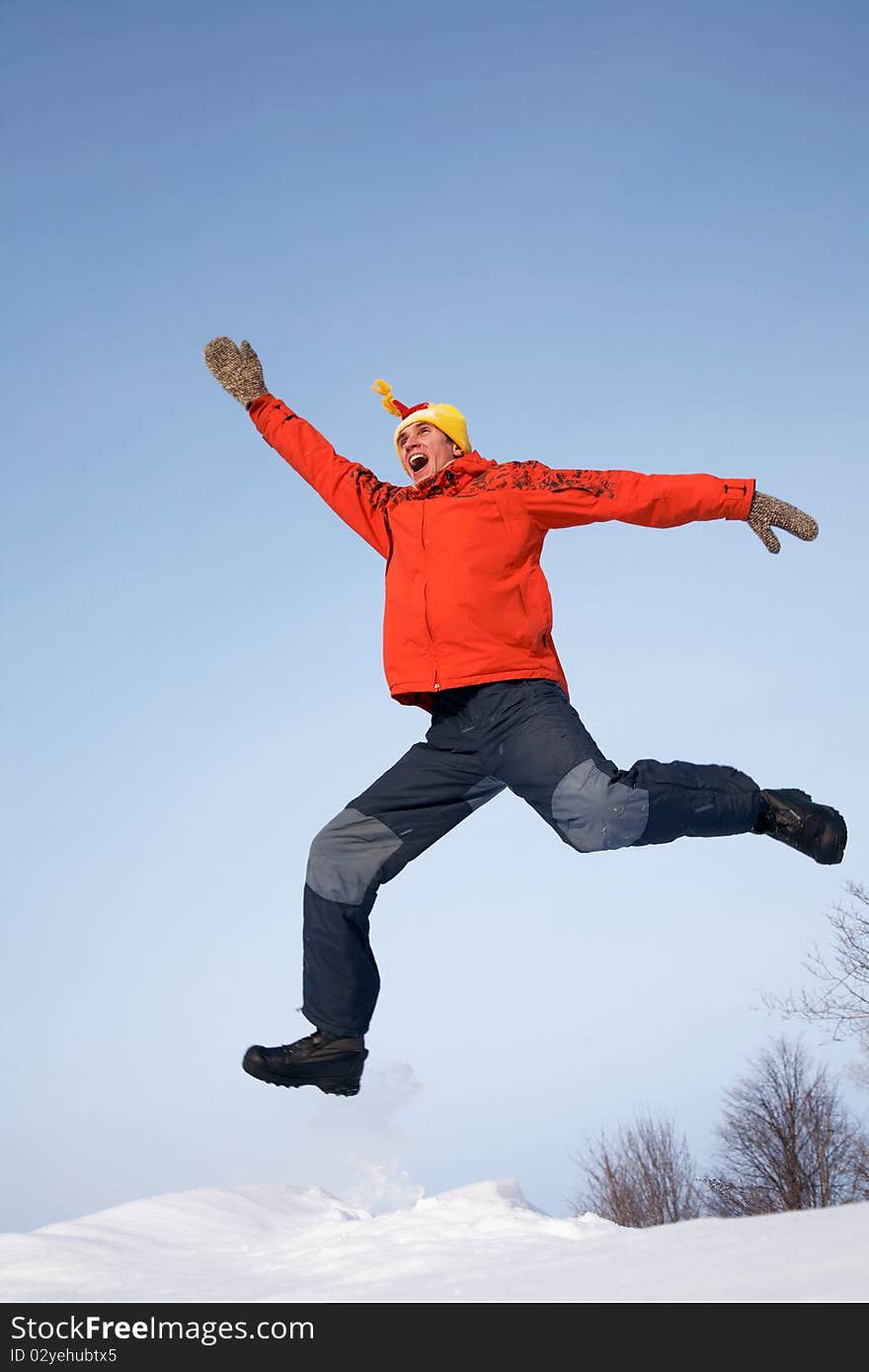 Young guy jumps with joy in the winter