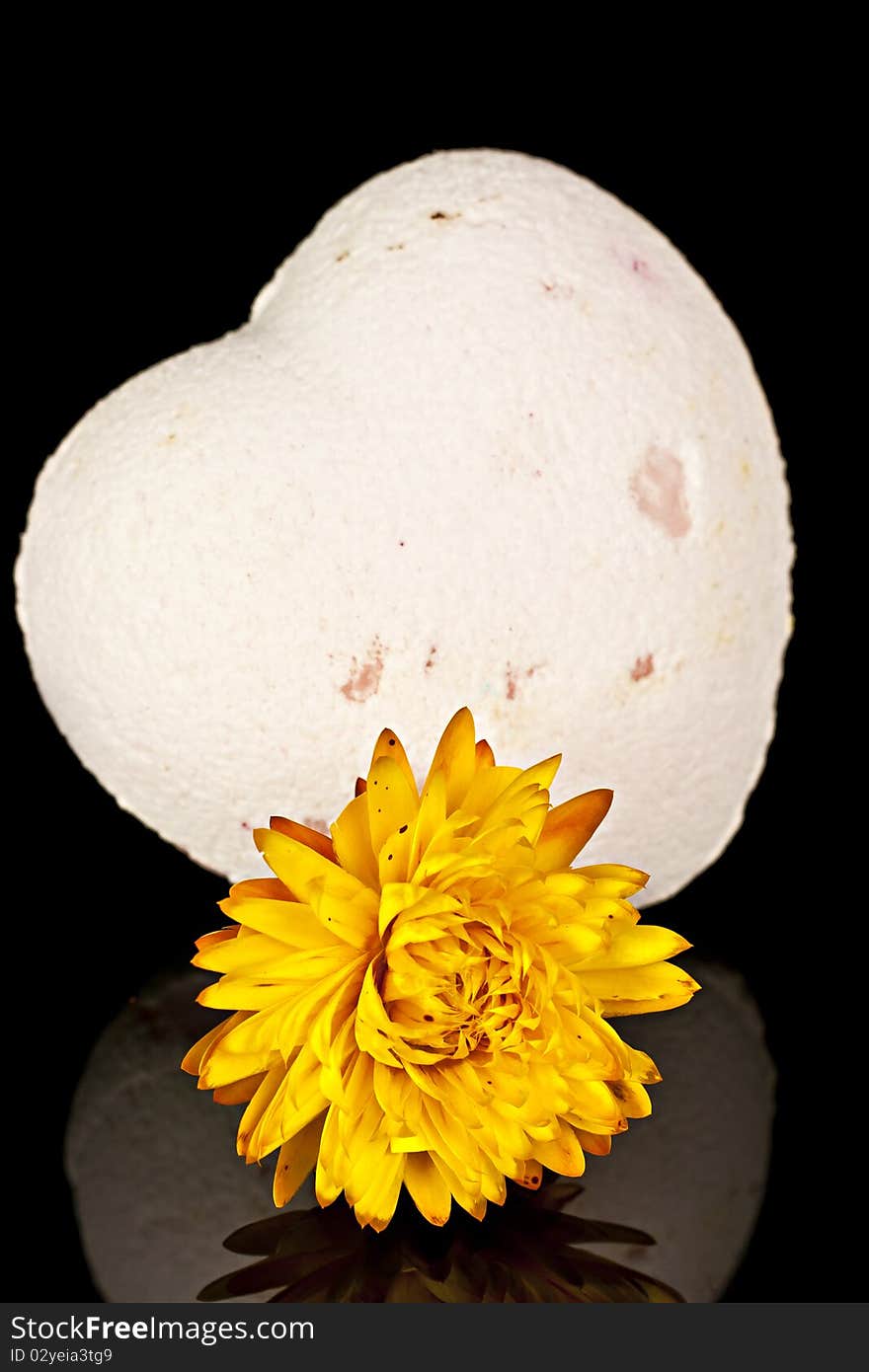 Bath salts in the form of the heart with a dry yellow flowers on a black background. Bath salts in the form of the heart with a dry yellow flowers on a black background.