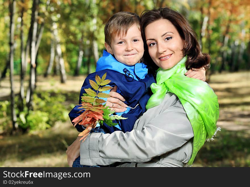 Happy mother walking at the autumn park with her son. Happy mother walking at the autumn park with her son.