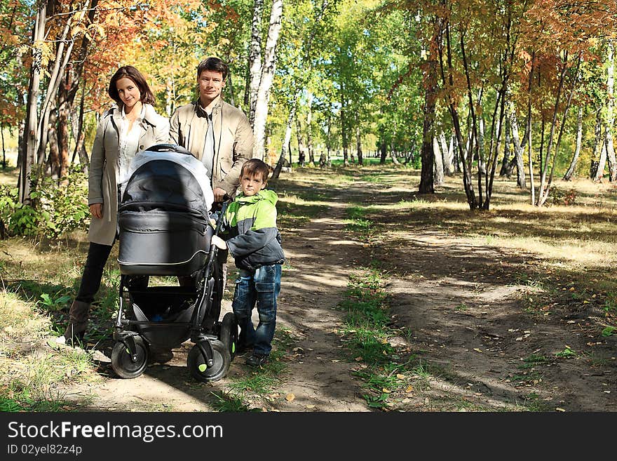 Happy family with two children walking at the autumn park.