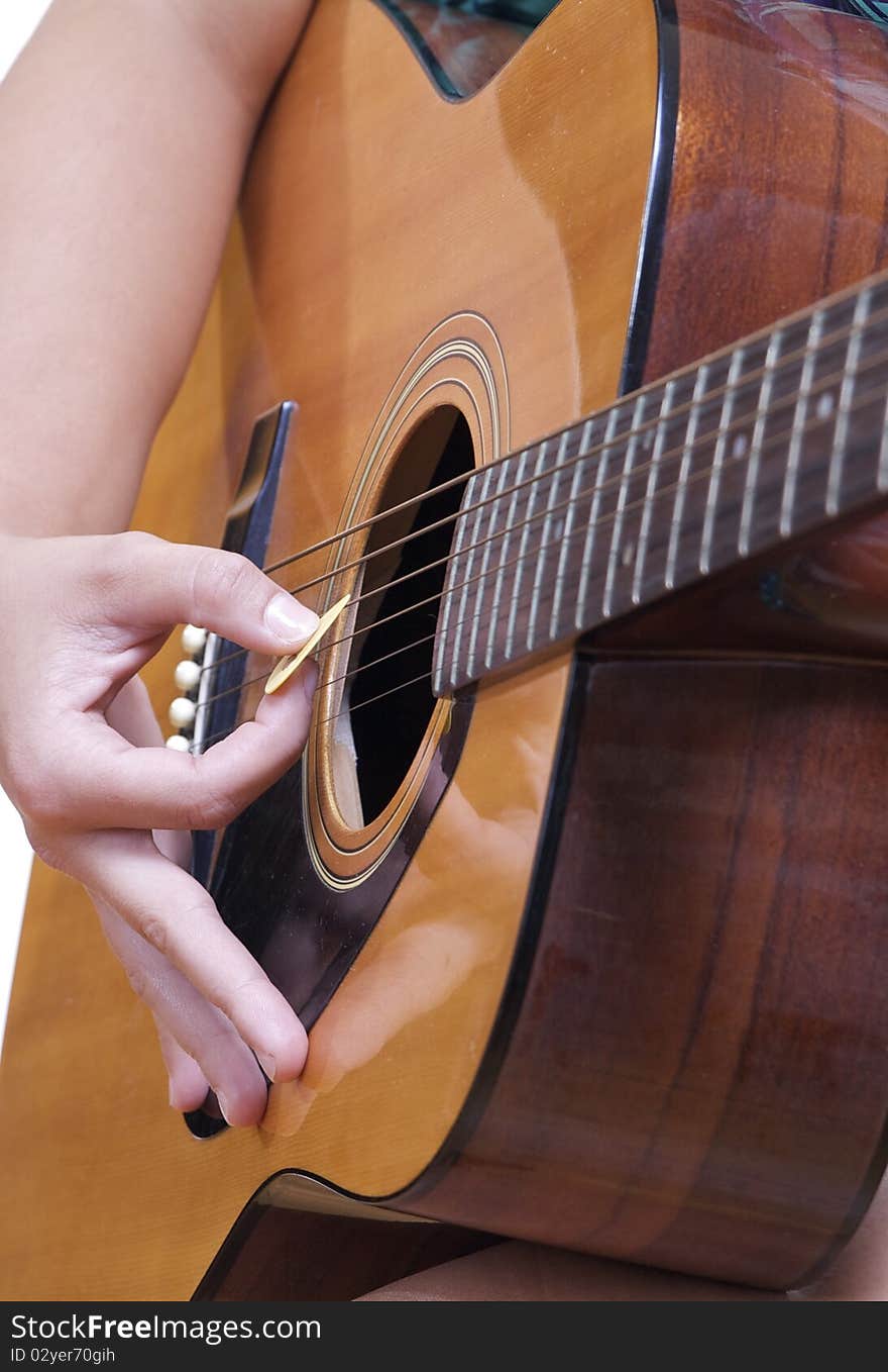 An Accoustic Guitar is played by a caucasian female hand.