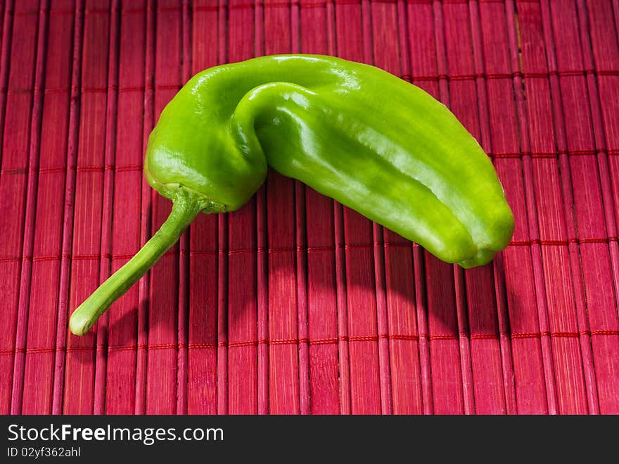 Green pepper on a red mat