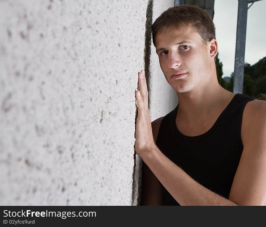 Young teenage boy leaning against a wall in anurban setting. Young teenage boy leaning against a wall in anurban setting.