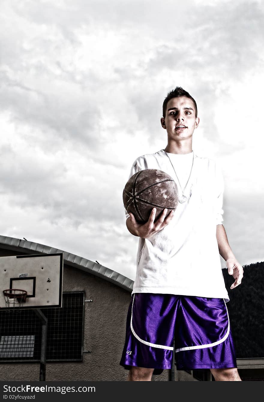 Young stylish teenage basketball player on the street with dark clouds over him. Young stylish teenage basketball player on the street with dark clouds over him.