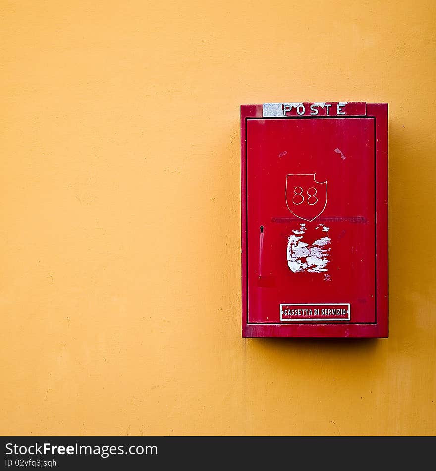 Photo of a red postal box on a yellow wall. Photo of a red postal box on a yellow wall