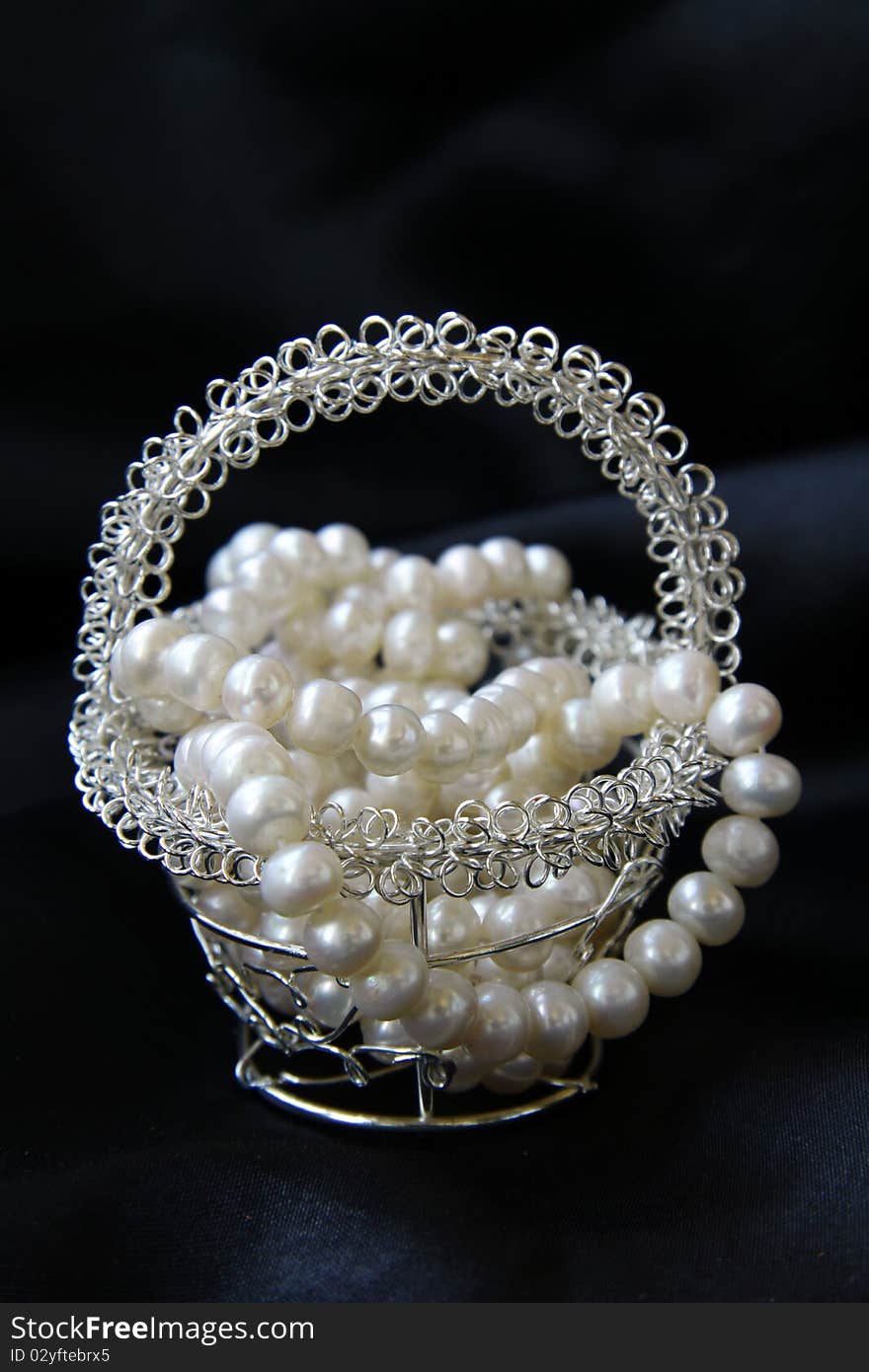 Jewelry pearls in a silver basket on a black background. Jewelry pearls in a silver basket on a black background