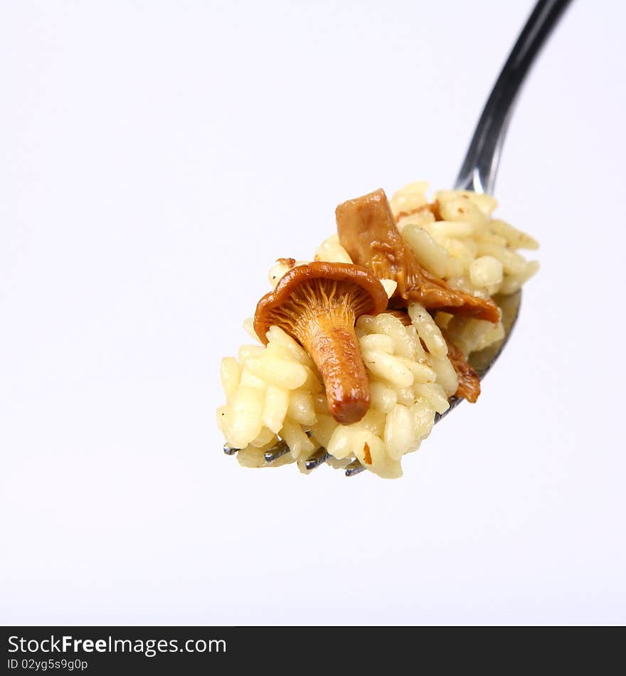 Risotto with mushrooms on a fork on white background