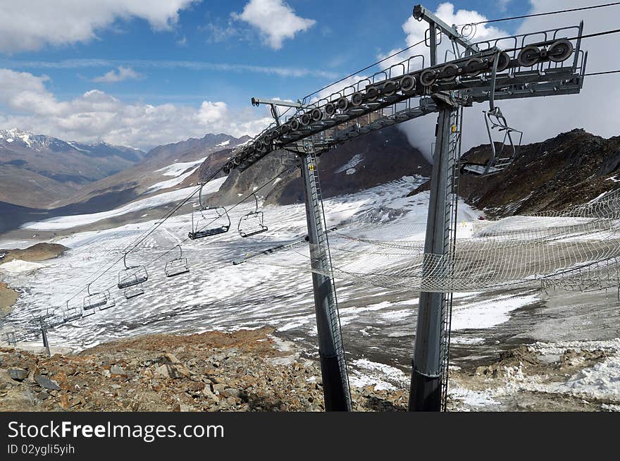 Ski resort in the Dolomites, chair-lift with glacier and mountains in the background.