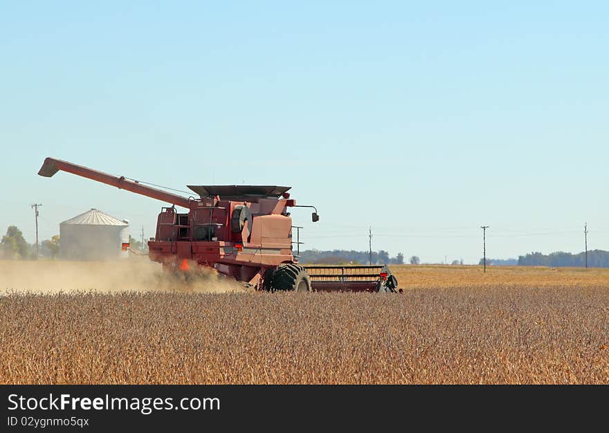 Red combine harvesting soybeans on a clear day