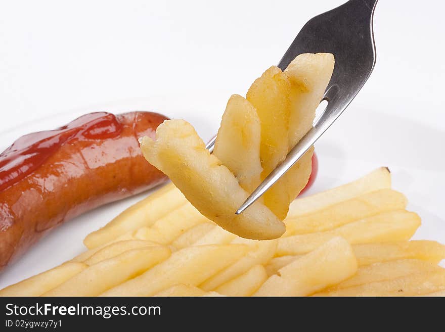 Fried potato on a fork, in a plate tomatoes and sausage.