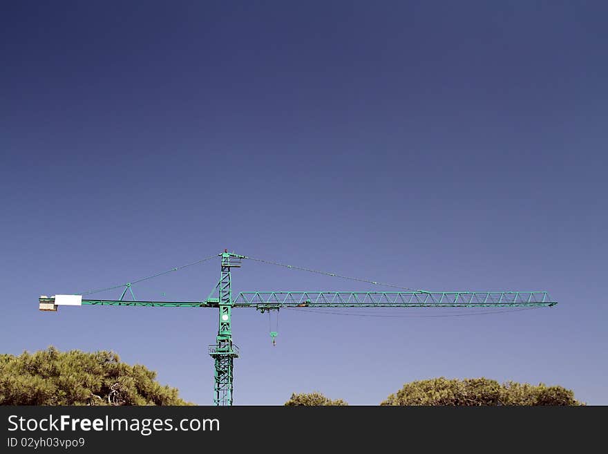 Lifting crane & trees on sky background. abstract industrial image