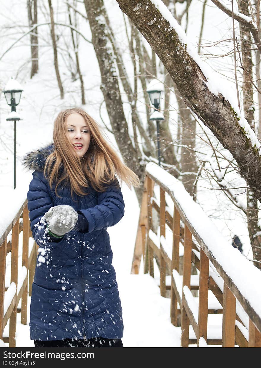 Young woman in blue coat outdoors playing with snow in snow forest. Young woman in blue coat outdoors playing with snow in snow forest