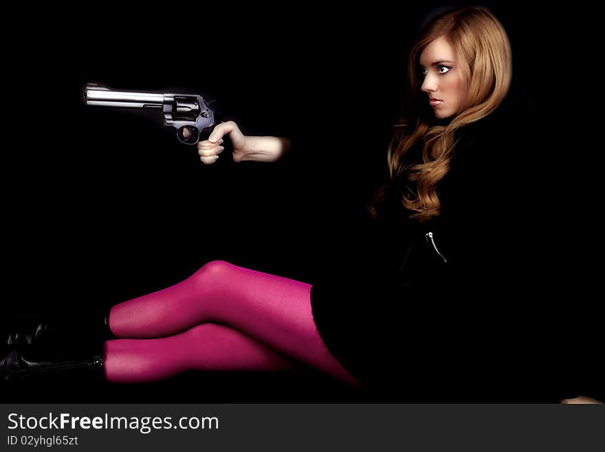 A woman sitting and looking away while holding a gun with pink tights. A woman sitting and looking away while holding a gun with pink tights.