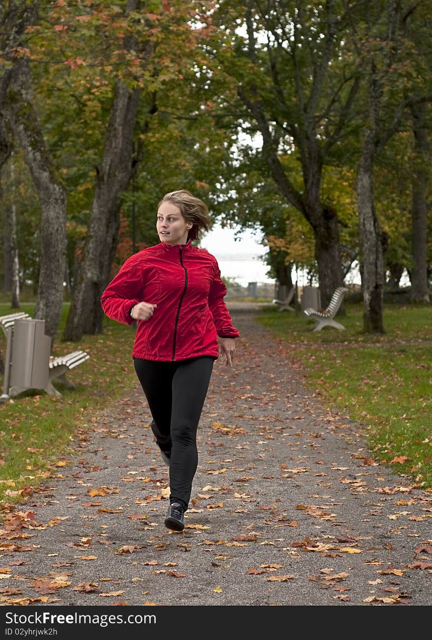 Beautiful female athlete running in park on a beautiful autumn day. Beautiful female athlete running in park on a beautiful autumn day.