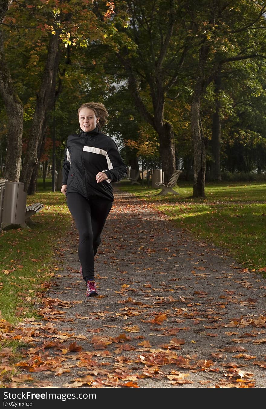 Beautiful female athlete running in park on a beautiful autumn day. Beautiful female athlete running in park on a beautiful autumn day.