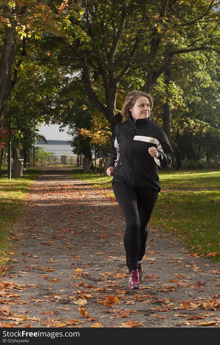 Beautiful female athlete running in park on a beautiful autumn day. Beautiful female athlete running in park on a beautiful autumn day.