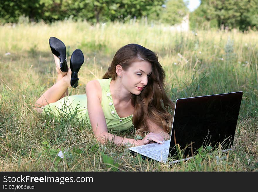 Beautiful woman lying on grass with laptop. Beautiful woman lying on grass with laptop