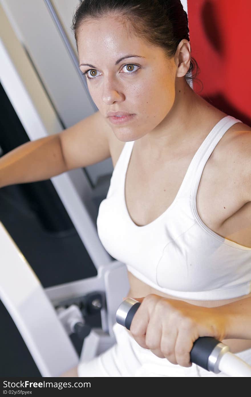 A caucasian woman works out on an exercise machine at the gym. A caucasian woman works out on an exercise machine at the gym.