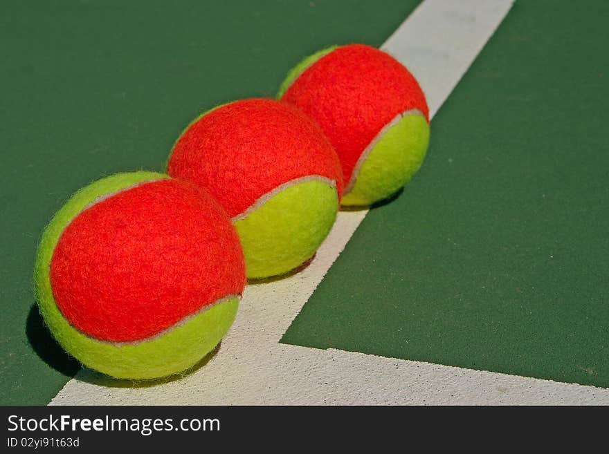 Yellow-red balls on a green tennis court. Yellow-red balls on a green tennis court