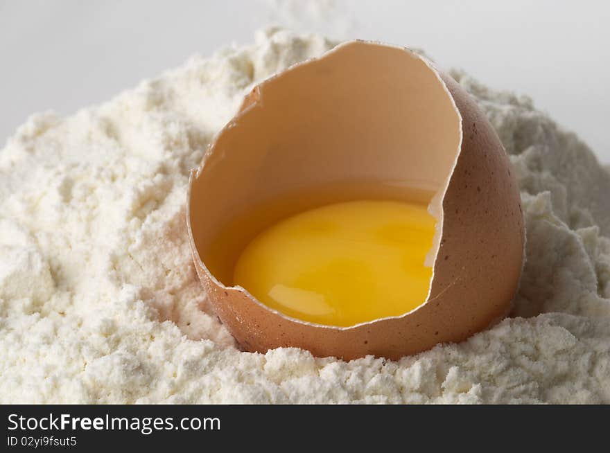 Broken eggshell and yolk in the flour macro shot. Broken eggshell and yolk in the flour macro shot