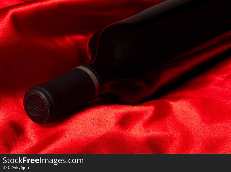 Bottle with red wine on a red silk