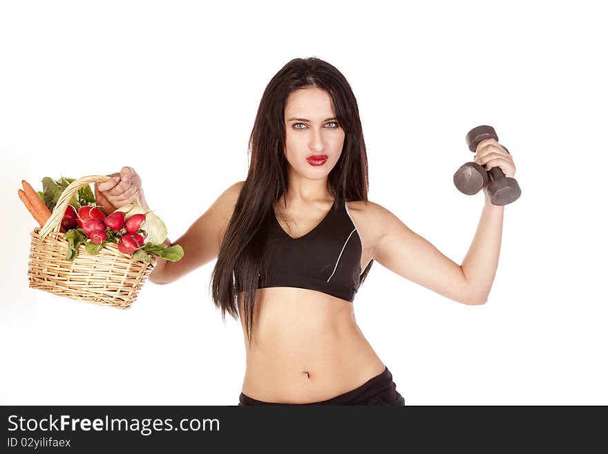 A woman is holding up a basket of vegetables and some weights. A woman is holding up a basket of vegetables and some weights.