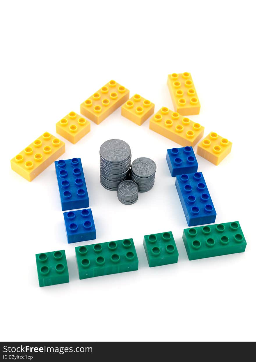 A house made from blocks with a stack of play money in the middle. A house made from blocks with a stack of play money in the middle