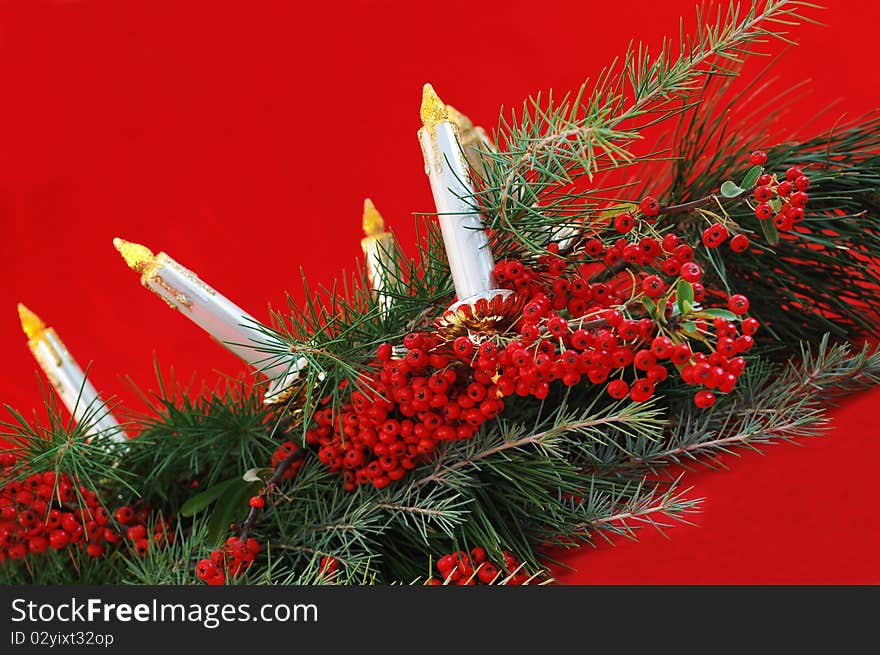 Green pine branches with canterberry, candles on red background. Green pine branches with canterberry, candles on red background