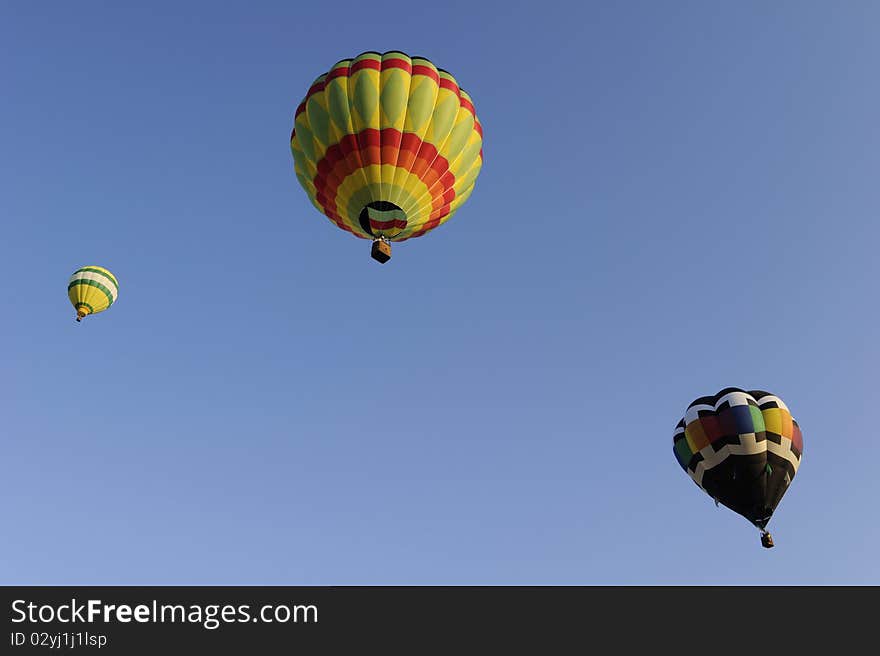 Three multi colored hot air balloons against a clear blue sky. Three multi colored hot air balloons against a clear blue sky