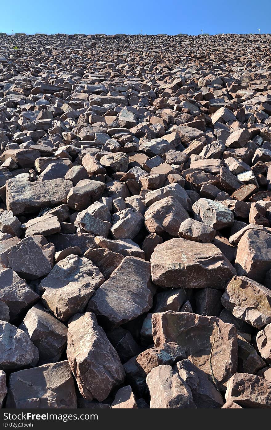 Construction area full of stone in brownness, under blue sky, shown as perspective and industrial solid and powerful. Construction area full of stone in brownness, under blue sky, shown as perspective and industrial solid and powerful.