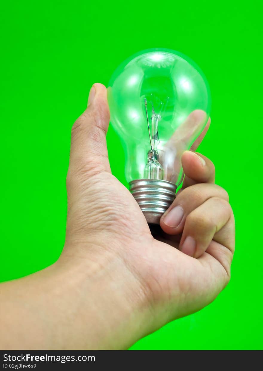 Lightbulb in a hand isolated on green background. Lightbulb in a hand isolated on green background.