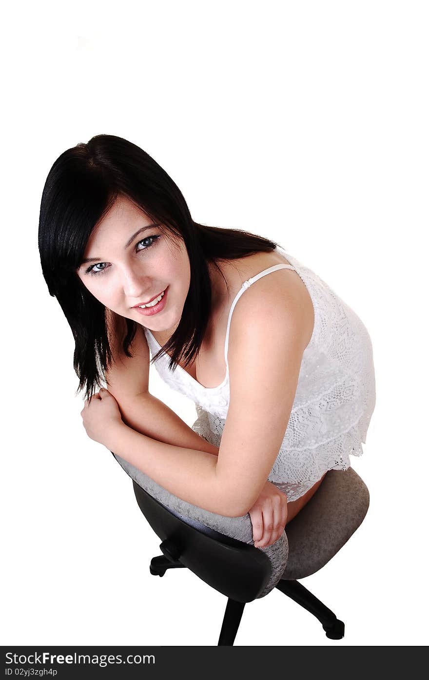 A young pretty woman kneeling on an office chair and looking up
into the camera, on white background. A young pretty woman kneeling on an office chair and looking up
into the camera, on white background.