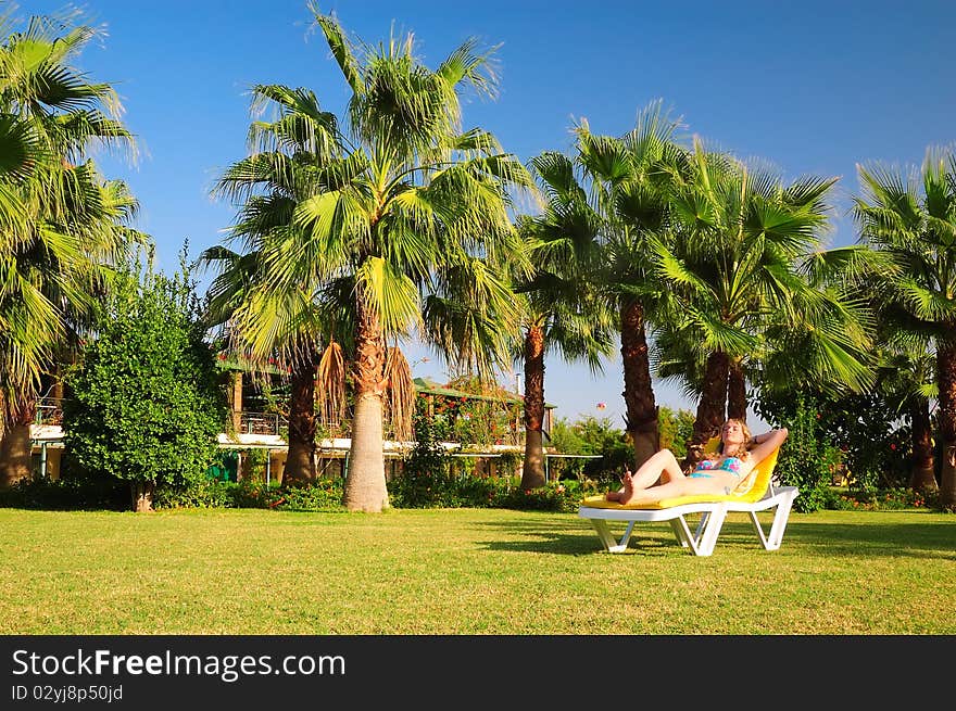 The teenager sunbathes near a palm tree. The teenager sunbathes near a palm tree