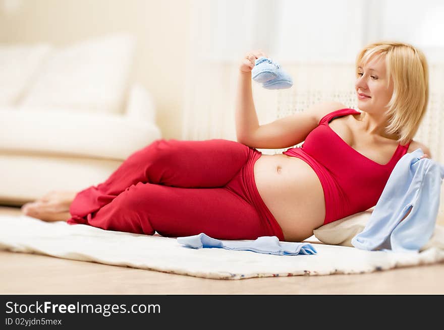 Happy pregnant woman holding baby clothes. Happy pregnant woman holding baby clothes