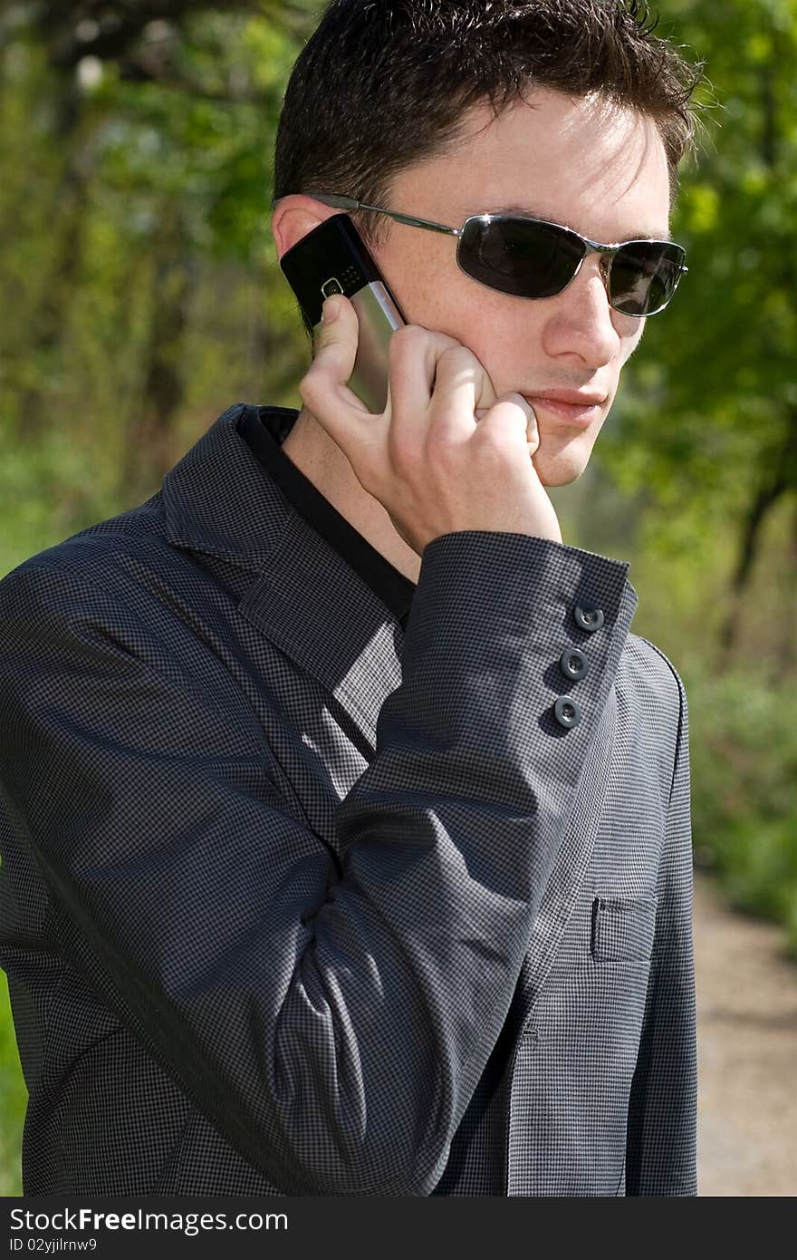 Man in sunglasses and jacket talks on cell phone