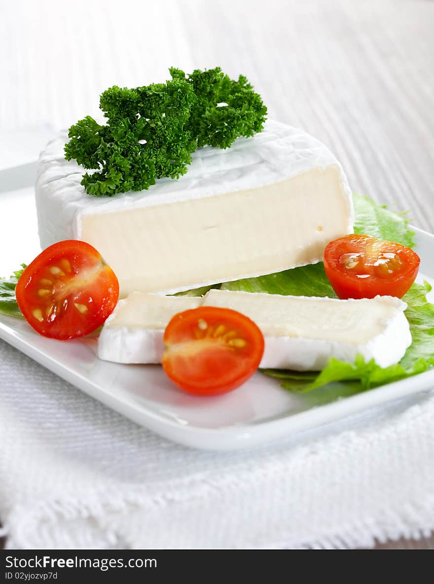 Soft cheese sliced on plate with tomato