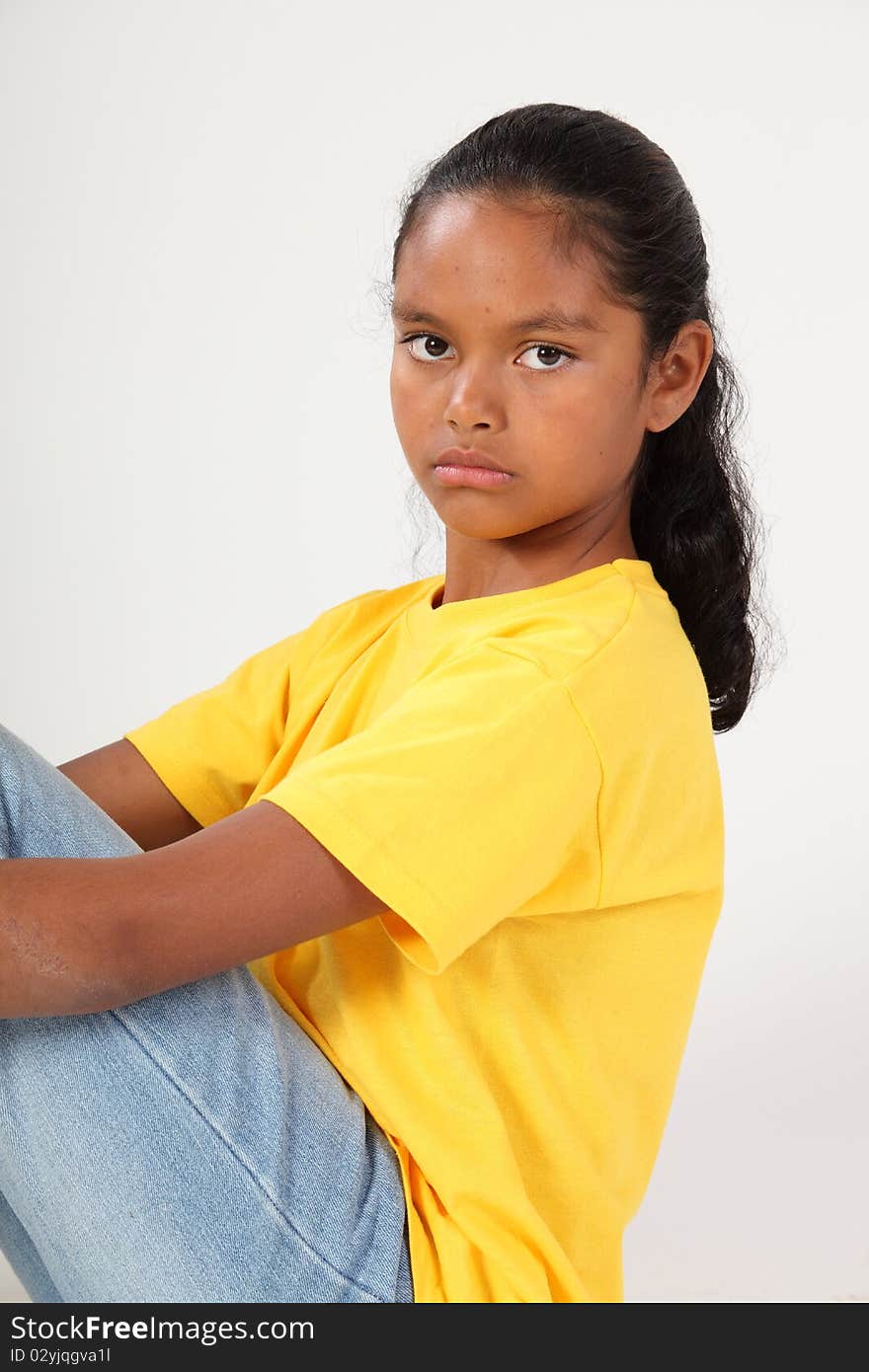 Close up portrait of serious young ethnic school girl, 9, staring straight at camera. Studio shot against white background. Close up portrait of serious young ethnic school girl, 9, staring straight at camera. Studio shot against white background