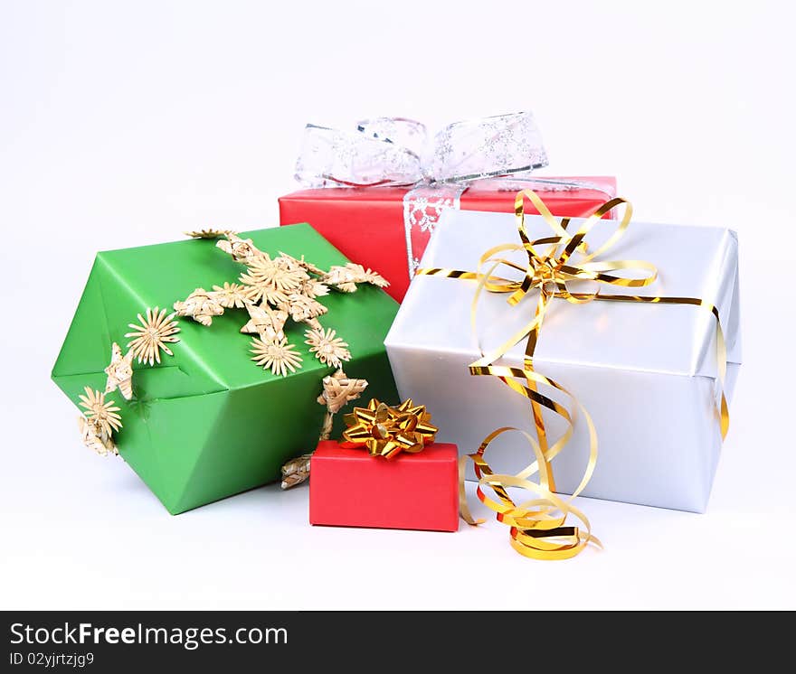 Gifts in silver, green and red wrapping with bows on white background. Gifts in silver, green and red wrapping with bows on white background