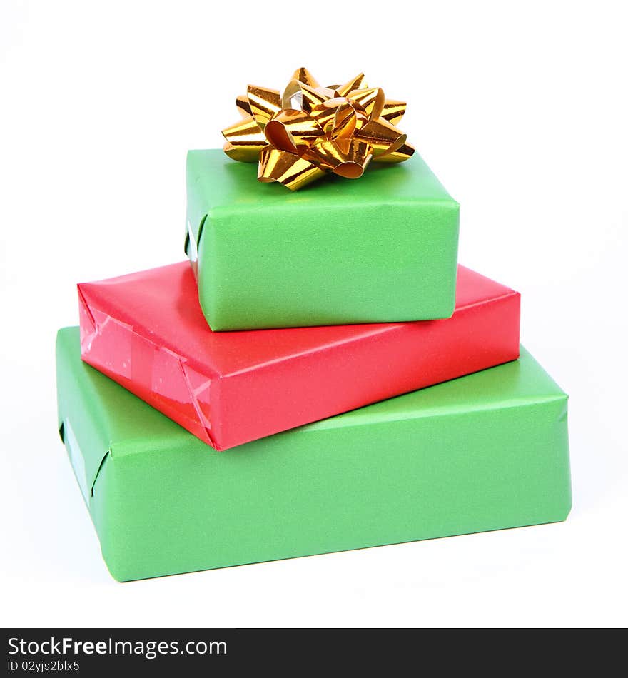 Gifts in green and red wrapping with a golden bow on white background