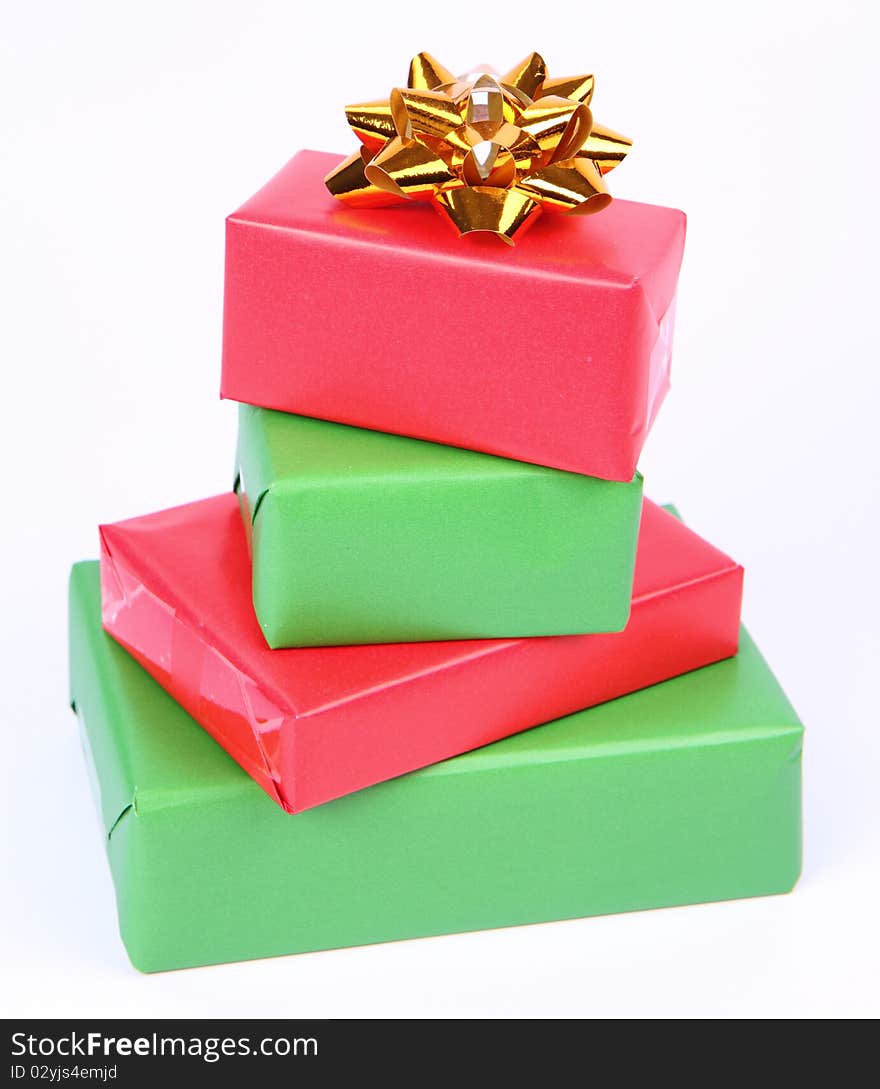 Gifts in green and red wrapping with a golden bow on white background