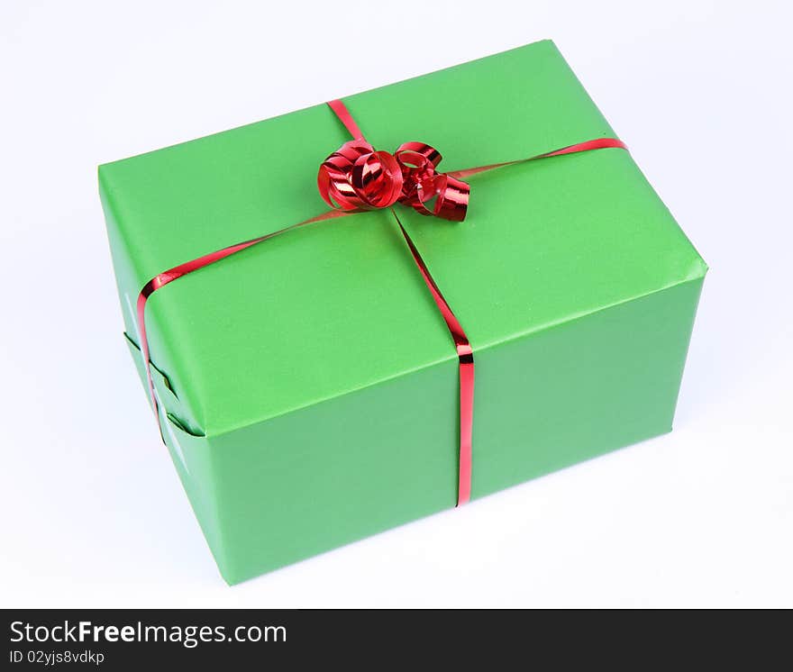 Gift in green wrapping with a red bow on white background