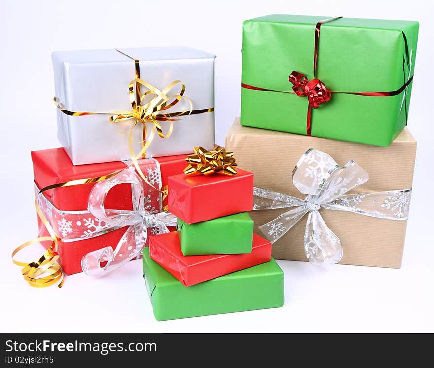 Gifts in silver, green, brown and red wrapping with bows on white background