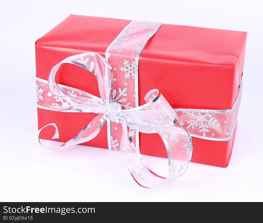 Gift in red wrapping with silver bow on white background