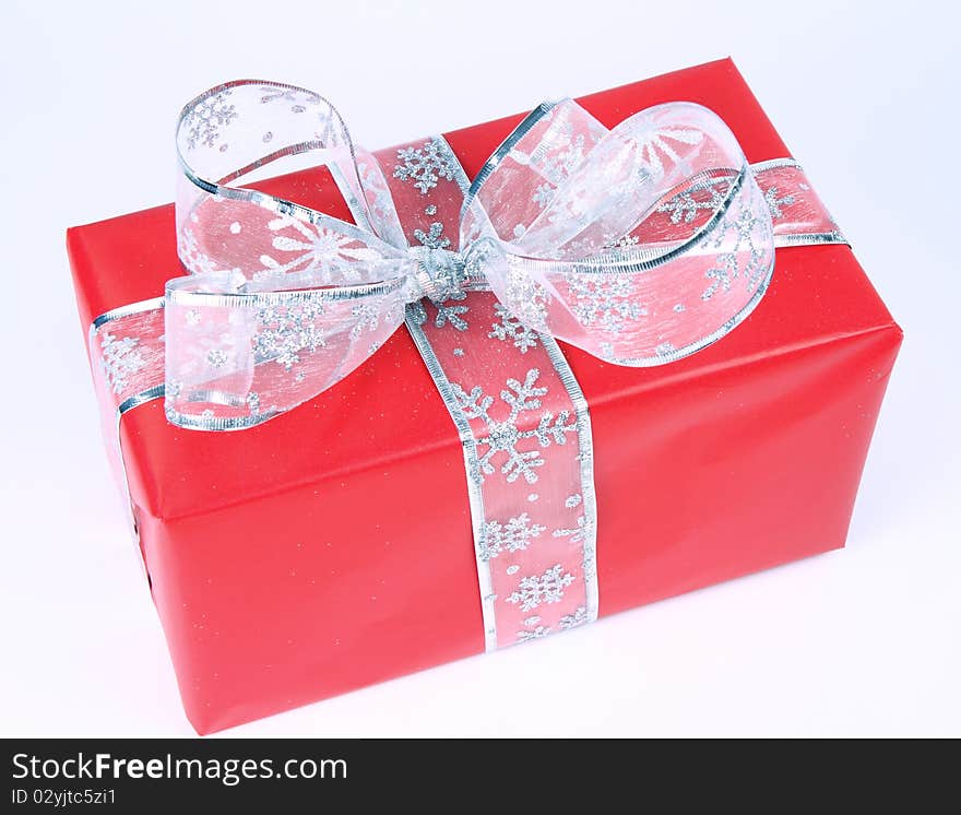 Gift in red wrapping with silver bow on white background