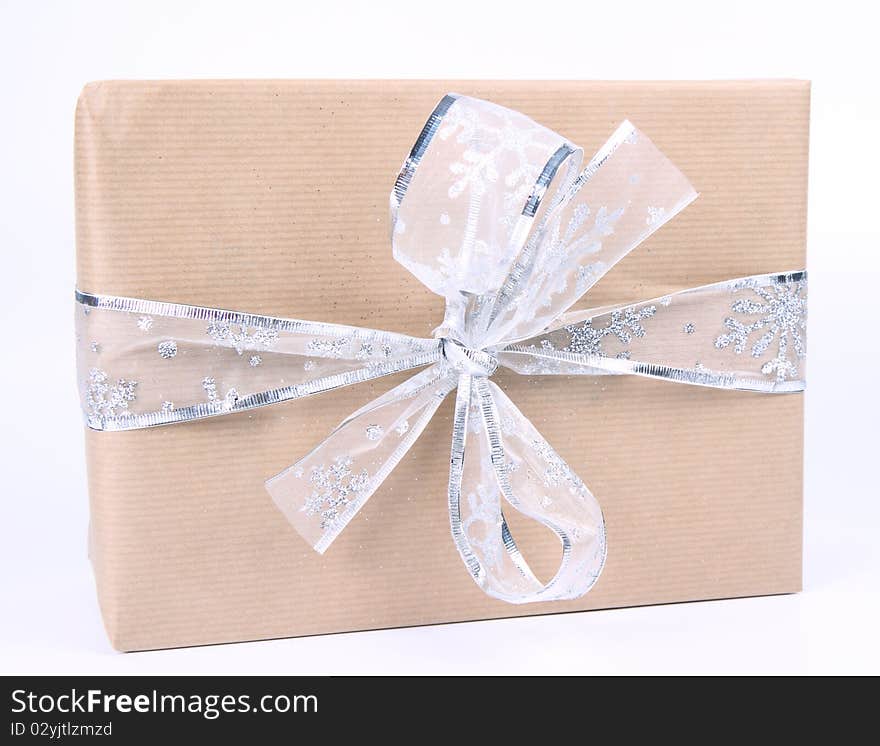 Gift in paper wrapping with silver bow on white background