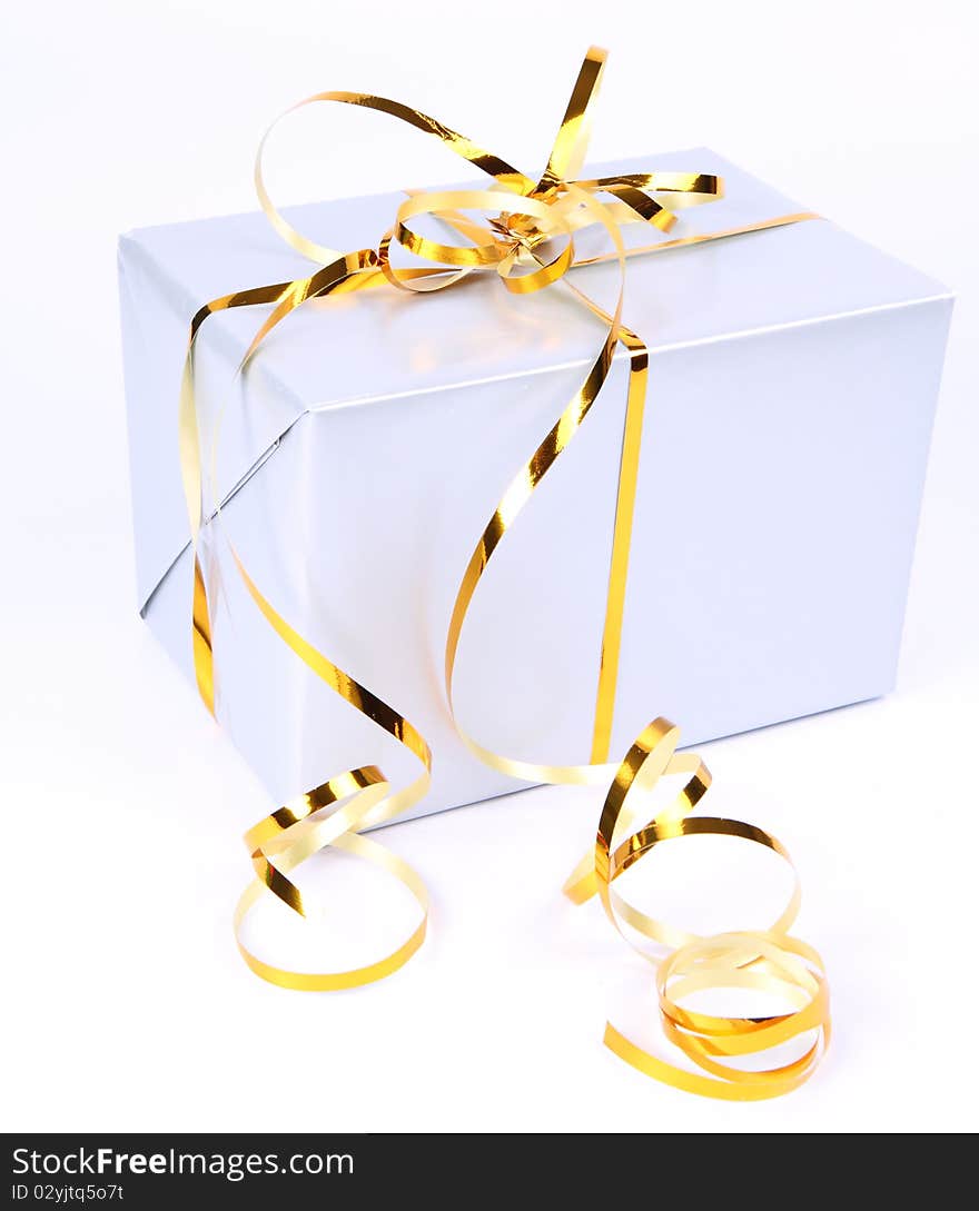 Gift in silver wrapping with gold bow on white background