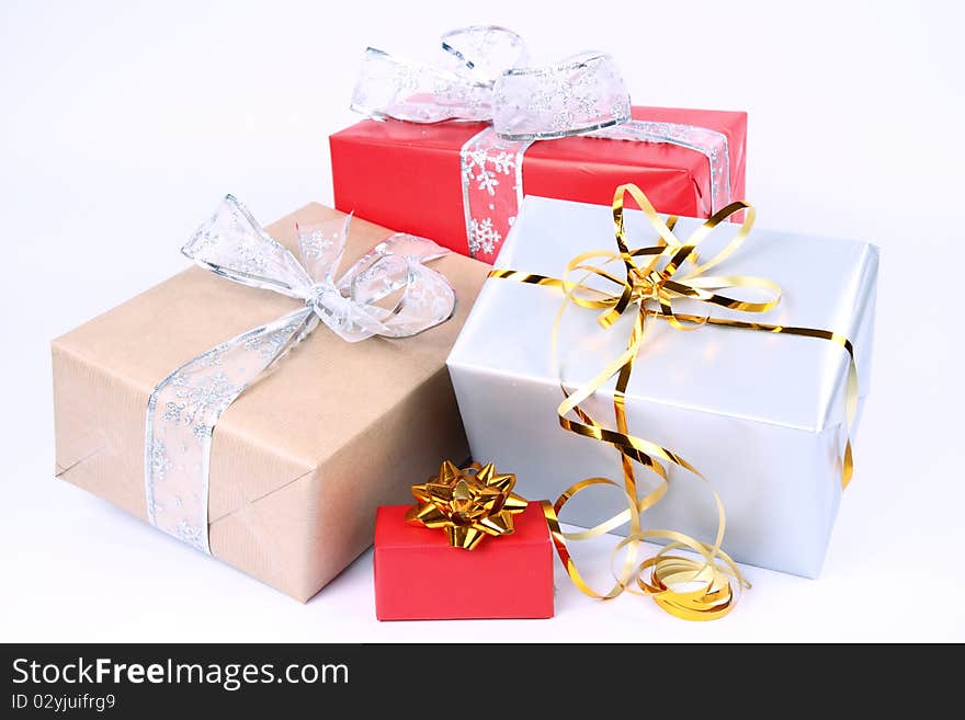 Gifts in silver, brown and red wrapping with bows on white background. Gifts in silver, brown and red wrapping with bows on white background