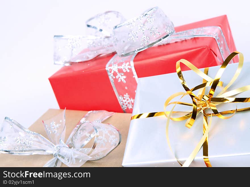 Gifts in silver, brown and red wrapping with bows on white background in close up