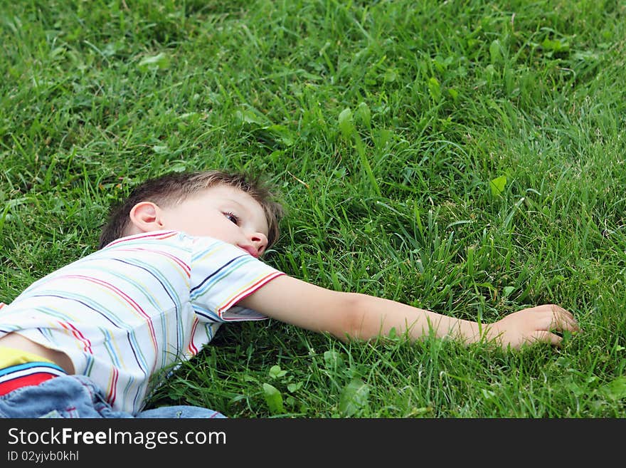 Tired boy relaxing in the grass, after the big running. Tired boy relaxing in the grass, after the big running