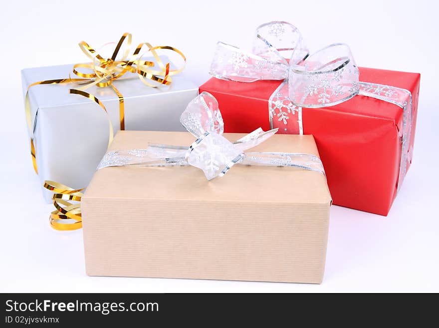 Gifts in silver, brown and red wrapping with bows on white background. Gifts in silver, brown and red wrapping with bows on white background